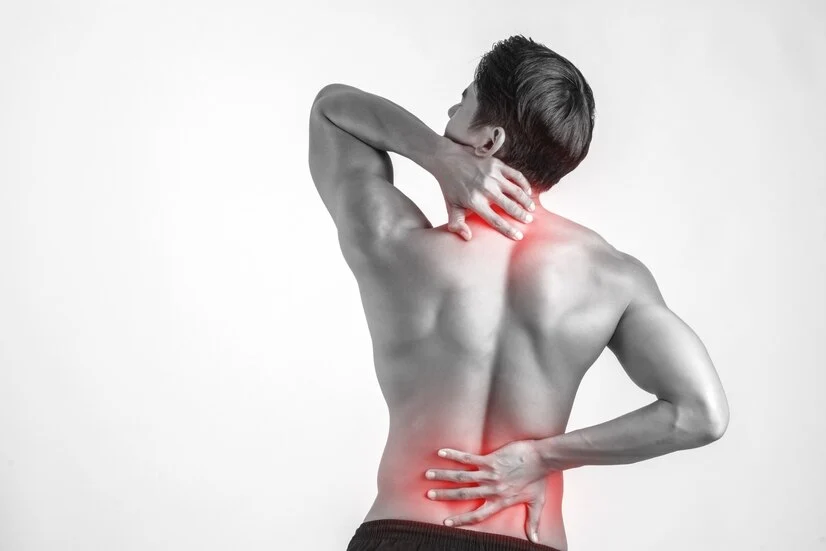 Male experiencing discomfort from low back pain against white backdrop.