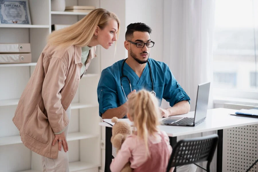 A man and woman explaining EHR system in family practice to a child using a laptop.