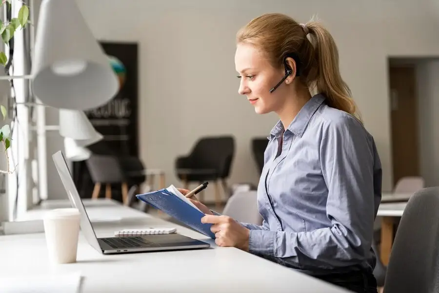 A woman with headphones and notepad, researching Medical Billing Company.